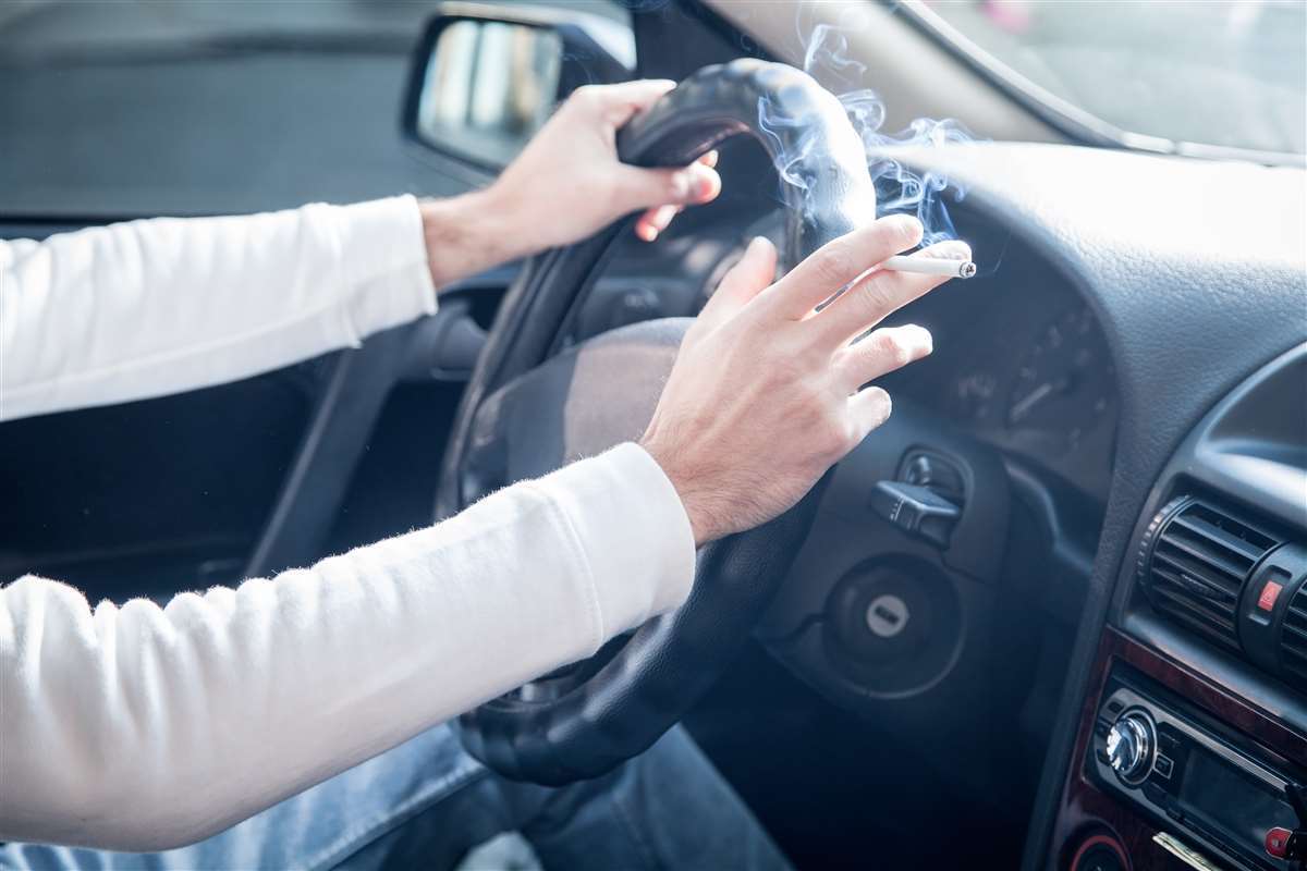 persona al volante di una automobile che fuma una sigaretta