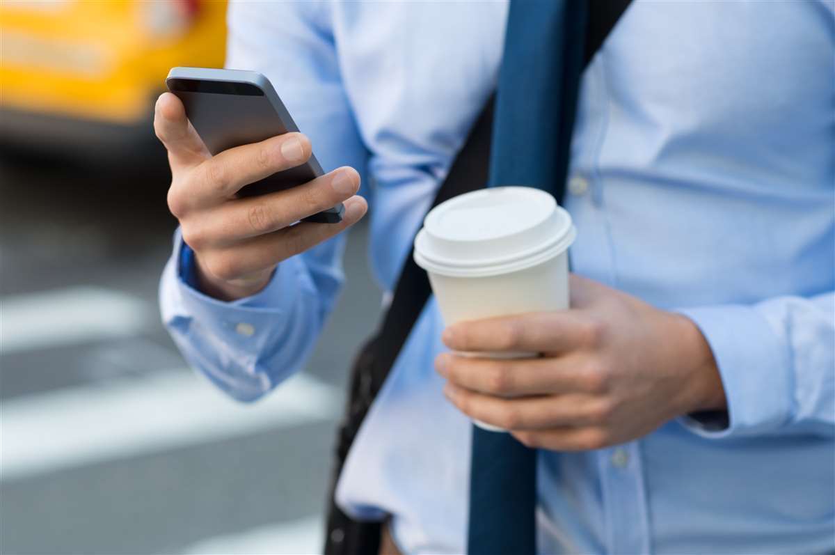 uomo con in mano smartphone e caffè