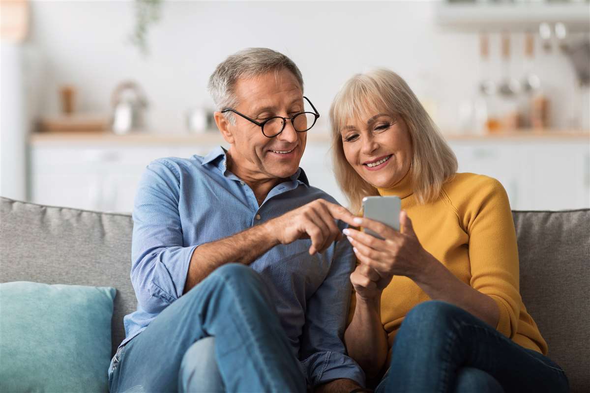 coppia di mezza età usa smartphone sul divano