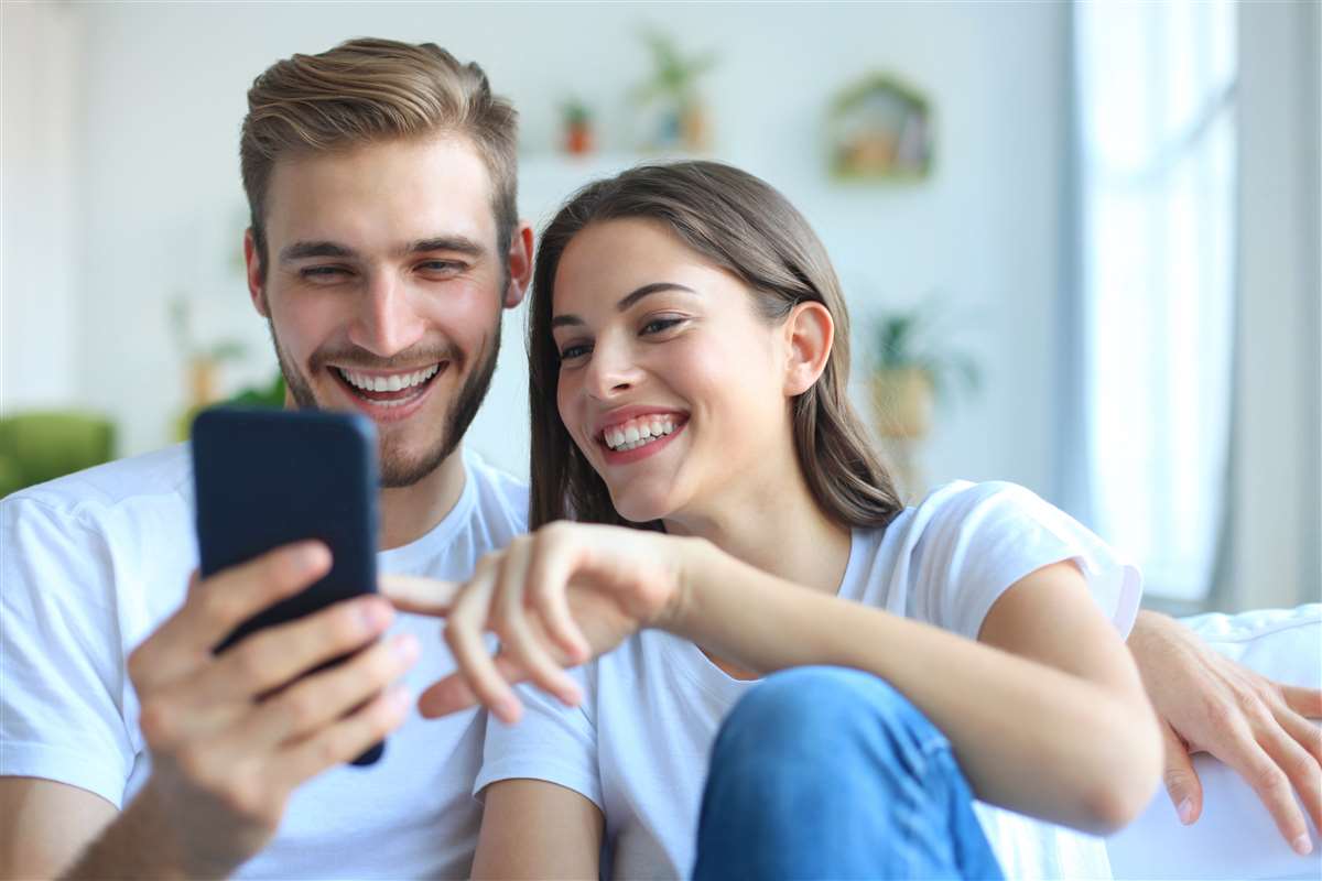 coppia felice usa smartphone sul divano di casa