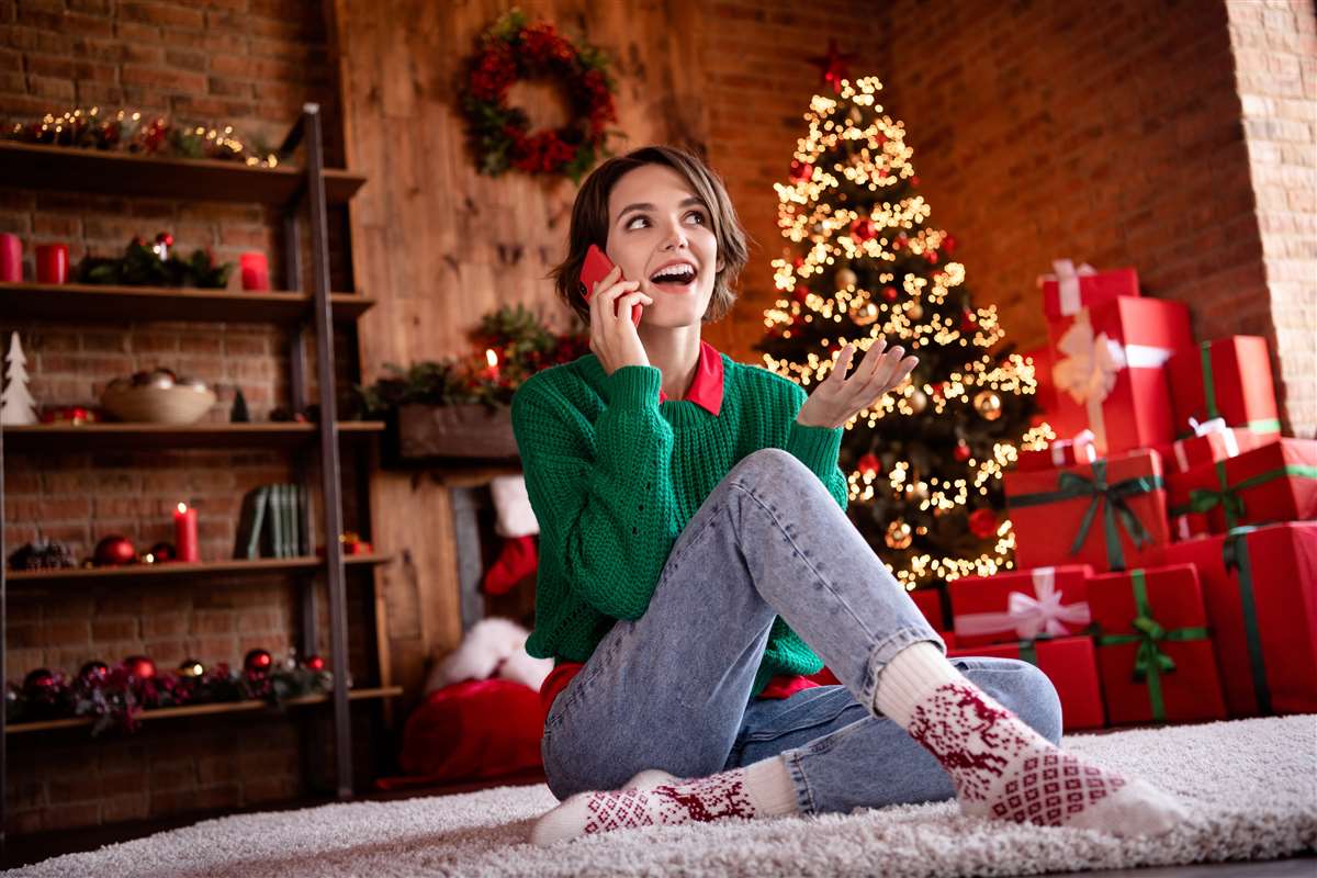 ragazza sorridente parla al cellulare in stanza con addobbi natalizi