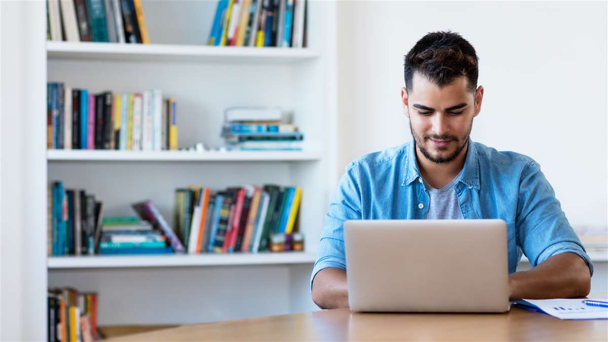 giovane uomo che scrive al computer con alle spalle una libreria