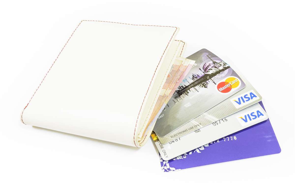Portafoglio bianco dal quale fuoriescono banconote e carte di credito