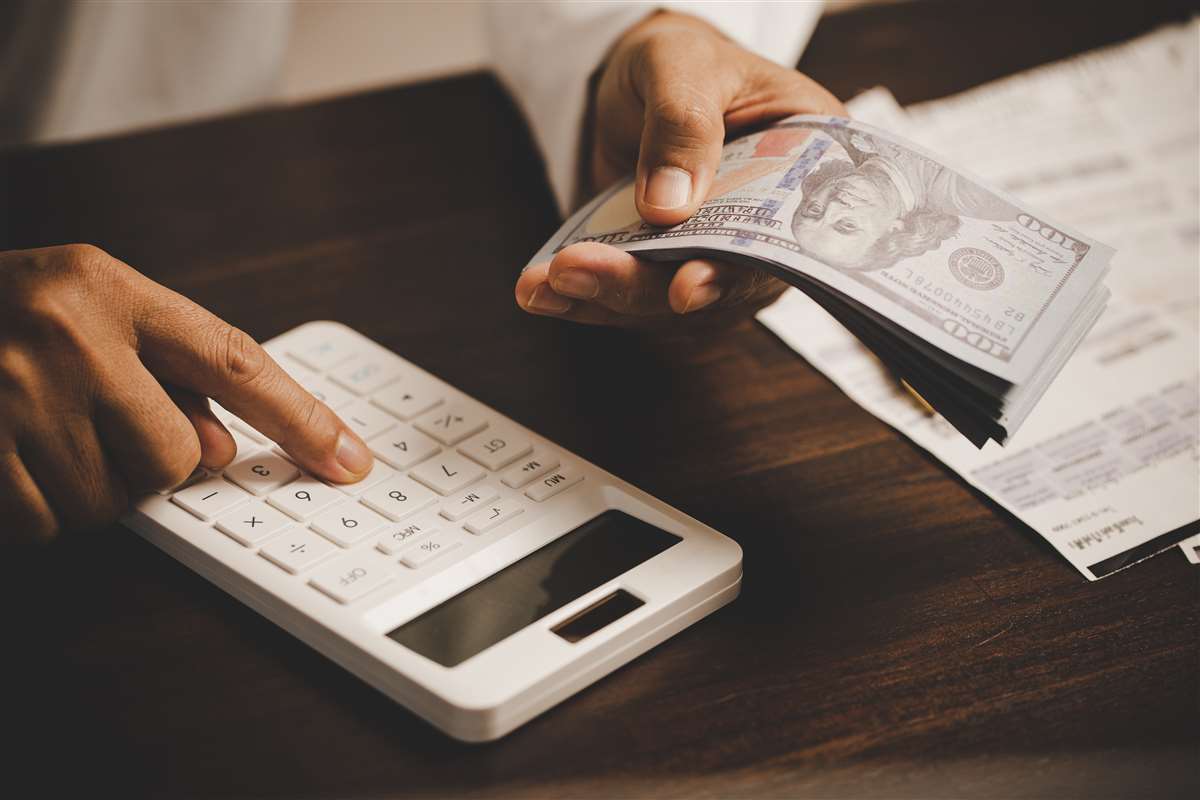 Tassa di concessione governativa persona che conta i dollari con una calcolatrice