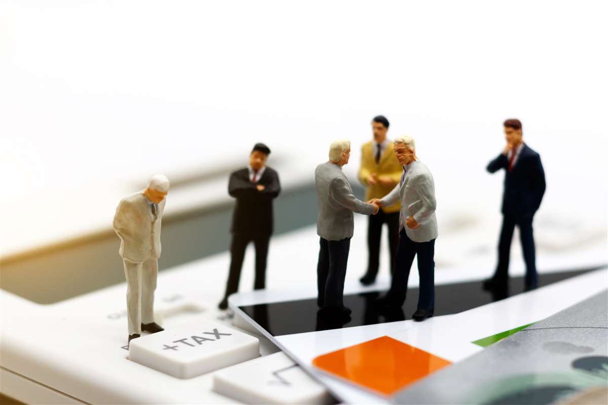 Miniature di uomini d'affari che si stringono la mano su una tastiera