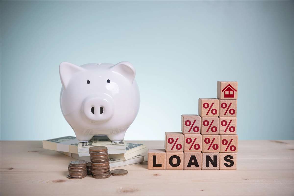 tassi prestiti salvadanaio vicino a cubi impilati che formano la scritta loans, insieme a simboli percentuali